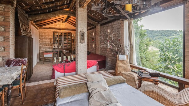 Una habitación rústica con techo de madera, una cama, una mesa de comedor y vistas al exterior.