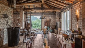 Comedor rústico con vigas de madera a la vista, paredes de piedra y vistas al exterior.