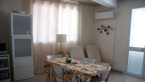 A dining area with a table set for two, a white cabinet, a lamp, and a window with curtains. - Holiday home in Nieuw-Loosdrecht (Torre Colonna-Sperone)