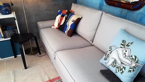 A modern living room with a grey sofa, two patterned cushions, a black stool, and a patterned rug. - Holiday home in Nieuw-Loosdrecht (Torre Colonna-Sperone)
