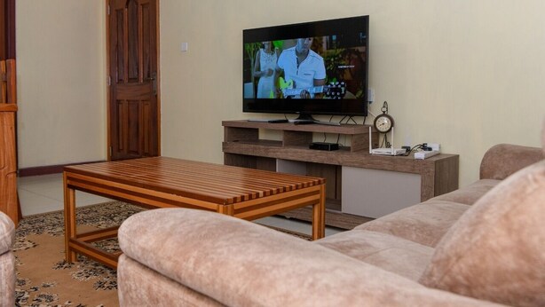 A living room with a television, wooden coffee table, and a sofa. - Stay.Plus Airport Transit House (Syokimau)
