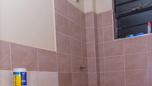 A bathroom with a toilet, shower, and a blue mat on the floor. - Stay.Plus Airport Transit House (Syokimau)