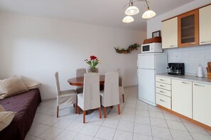 Espaço compacto com área de refeições, cozinha compacta e uma cama.