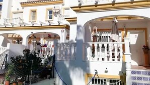 A white building with balconies, a covered entrance, and potted plants. - Belvilla by OYO Cala I (Vera Playa)