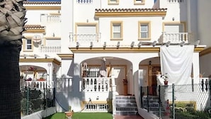 A courtyard with a fountain, a white building with balconies, and a covered seating area. - Belvilla by OYO Cala I (Vera Playa)