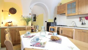 A dining area with a table set for breakfast, wooden cabinets, and a kitchen in the background.