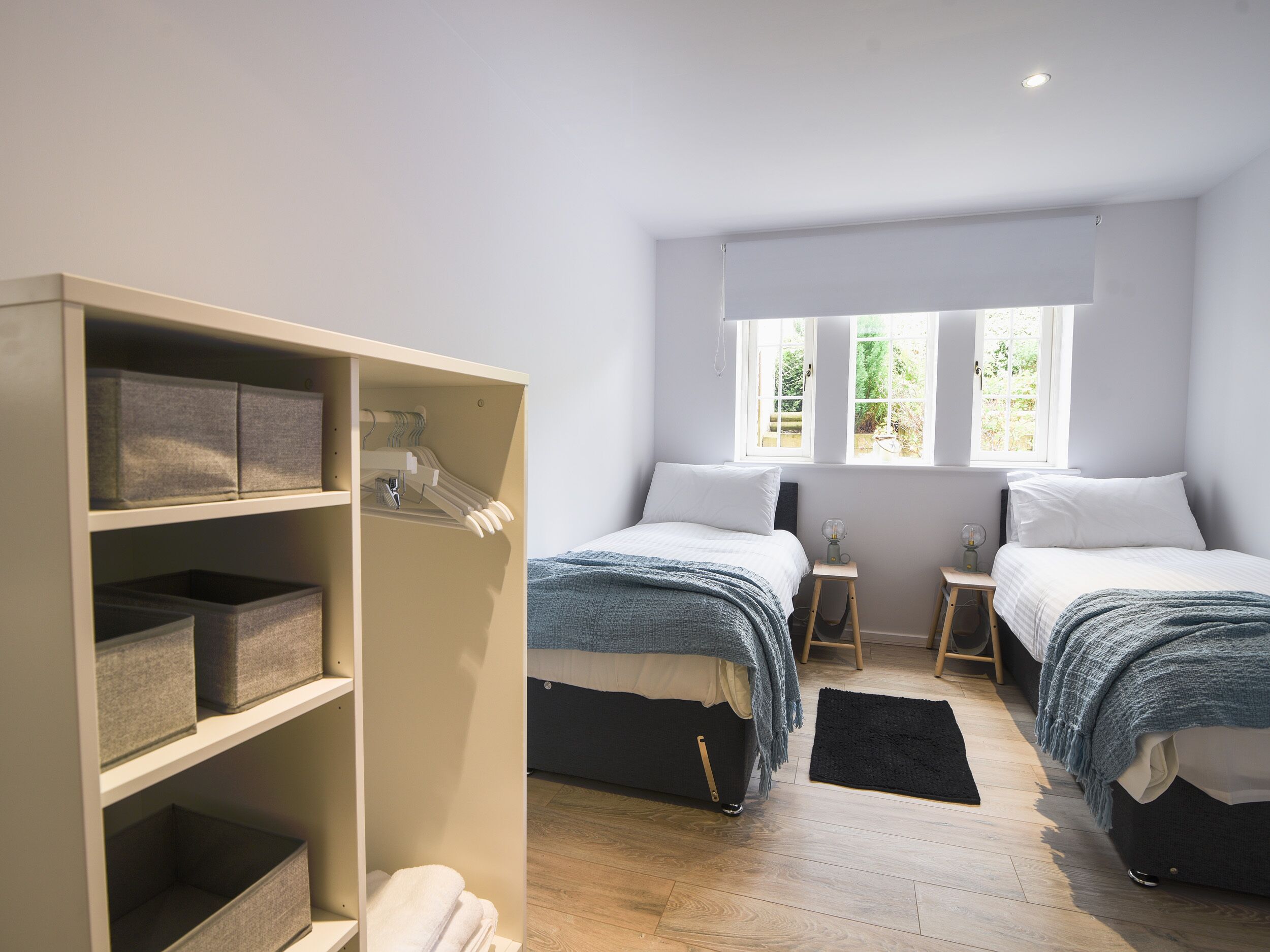 A bedroom with two beds, a wardrobe, and a window.