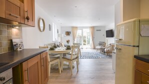 A compact kitchen with wooden cabinets, a dining area with a table and chairs, and a built-in TV.