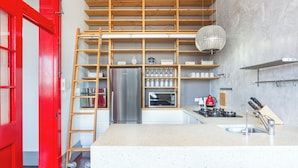 Een moderne keuken met een roestvrijstalen koelkast, houten planken en een rode deur.