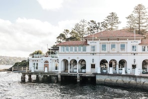 A waterfront building with multiple arches and a sign reading 'Manly Pavilion.'