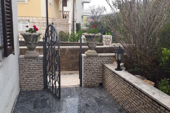 A gated entrance with a wrought iron gate, a stone pathway, and a brick wall.