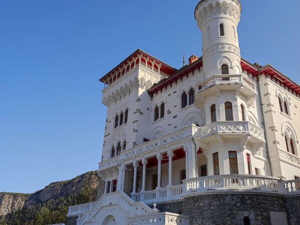 A large, ornate building with multiple balconies and a prominent tower.