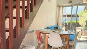 Ein Essbereich mit Holztisch, weißen Stühlen und einem blauen Sofa.