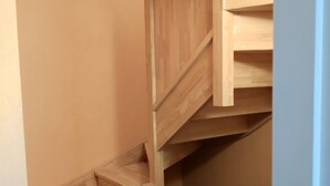Una escalera de madera con barandilla y rellano.