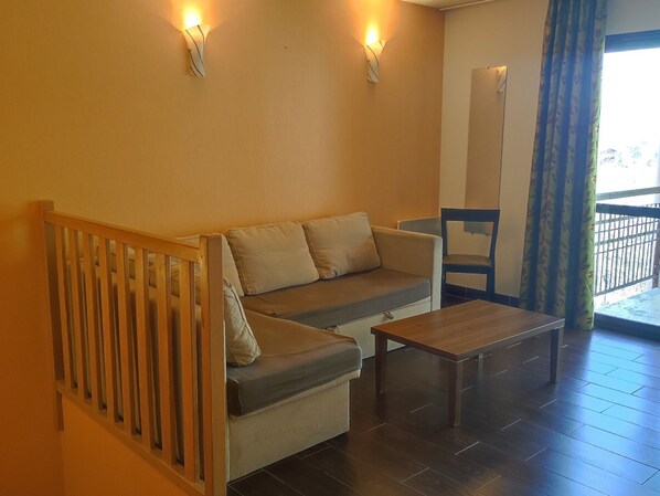 Una habitación amoblada con sofá, mesa de madera y una silla.