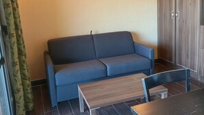 A room with a sofa, a wooden table, and a wardrobe.