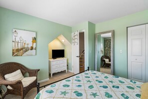 Een slaapkamer met een bed, een dressoir, een stoel en een schilderij aan de muur.