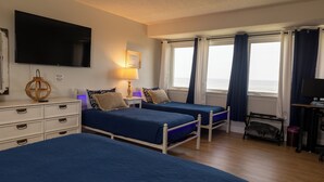 Habitació d'hotel amb dos llits, televisió, escriptori i vista al mar.