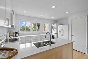 Una cocina moderna con horno empotrado, un lavamanos y un ventanal con vistas a palmeras.