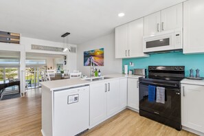 Een moderne keuken met witte kastjes, een zwarte Samsung oven en een blauwgroene achterwand.