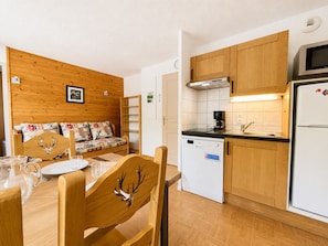 A compact kitchen with wooden cabinets, a built-in microwave, and a dishwasher. - Pleasant ski-in/ski-out apartment with pool (Flumet)