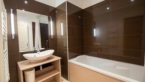 Een moderne badkamer met een ruime badkuip, een wastafel en een spiegel.