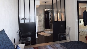 Una habitación de hotel moderna con una cama grande, un escritorio, una silla y zona de ducha.
