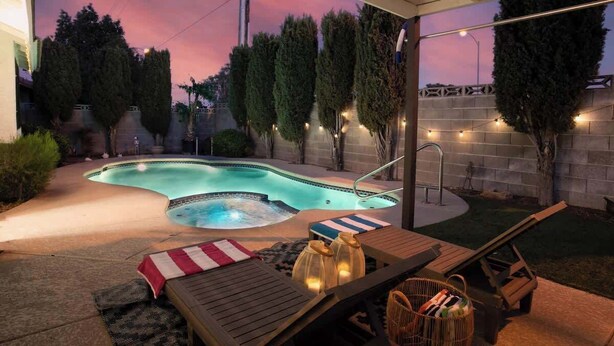 Ein Garten mit Schwimmbad, Liegestühlen und einer überdachten Terrasse.
