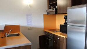 A compact kitchen with a built-in sink, a stove, a refrigerator, and wooden cabinets. - Duplex for 6 with heated pool and jacuzzi in Jausiers (Jausiers)