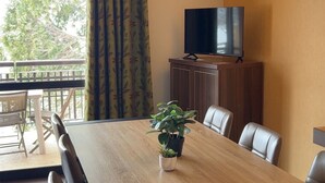 A conference room with a wooden table, leather chairs, a potted plant, a television on a cabinet, and a view of trees through a window with curtains. - Duplex for 6 with heated pool and jacuzzi in Jausiers (Jausiers)