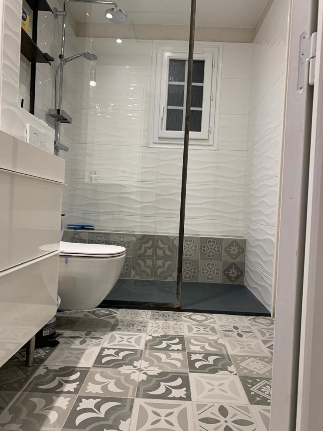 A bathroom with a toilet, shower, and a window.