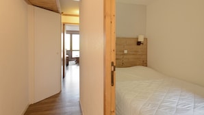 Un dormitorio con cabecera de madera, lámpara de noche y cubrecama blanco.