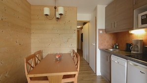 Cocina compacta con armarios de madera, microondas integrado y lavavajillas.