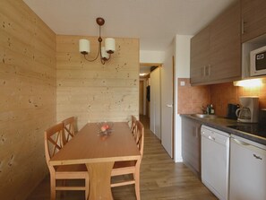 Cocina compacta con armarios de madera, microondas integrado y lavavajillas.
