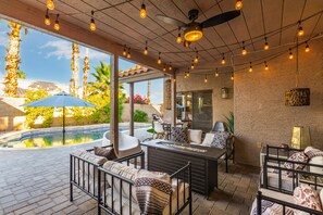 Une terrasse extérieure avec une piscine, un espace salon et des guirlandes lumineuses.