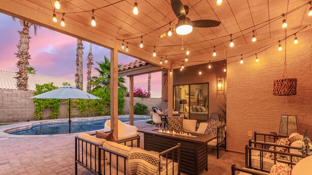 An outdoor patio with a pool, seating area, and string lights. - Updated 3BR Scottsdale Home | Heated Pool, Putting Green, Fire Pit (Scottsdale)