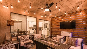 A cozy living area with a fireplace, comfortable seating, and a television mounted on a wooden wall. - Updated 3BR Scottsdale Home | Heated Pool, Putting Green, Fire Pit (Scottsdale)
