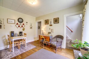 Ett mysigt rum med ett matbord i trä, två stolar, en fåtölj i rotting, en plats för att göra kaffe och en trappa som leder till en annan våning.