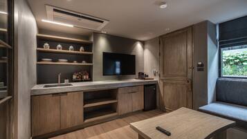 Una cocina moderna con televisor integrado, armarios de madera y una zona de estar con mesa y banco.
