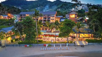 A beachfront hotel with multiple buildings, a pool area, and a dining terrace.