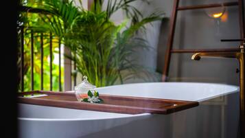 A bathroom with a bathtub, a wooden tray, and a glass container with flowers.