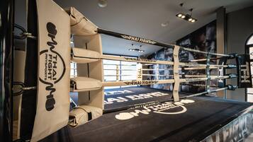 A boxing ring with Thai Fight branding, padded walls, and a black mat.
