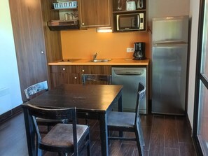 Compact kitchen area with microwave, refrigerator, sink, and coffee maker, perfect for small gatherings or individual use.