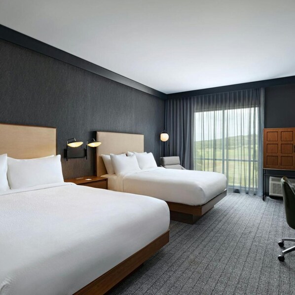 A hotel room with two beds, a desk, a chair, and a large window with curtains. - Courtyard Austin Dripping Springs (Dripping Springs)