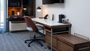 A modern hotel room with a desk, chair, flat-screen TV, and built-in air conditioning unit. - Courtyard Austin Dripping Springs (Dripping Springs)