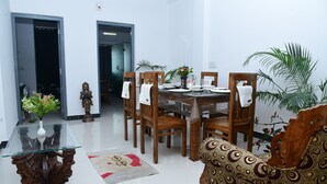 Un comedor con una mesa de vidrio, sillas de madera y un sofá estampado.