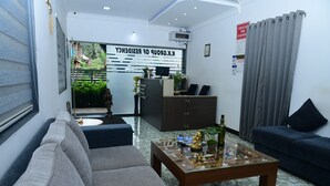 Una sala de estar moderna con un sofá, una mesa de centro con objetos decorativos, un mostrador de recepción y vistas al exterior.
