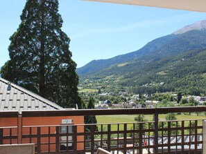 A balcony with a view of a village, mountains, and a tall tree. - Studio for 4 with terrace and pets allowed (Jausiers)