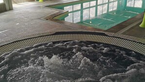 Boblebad med flisegulv og en pool i baggrunden.