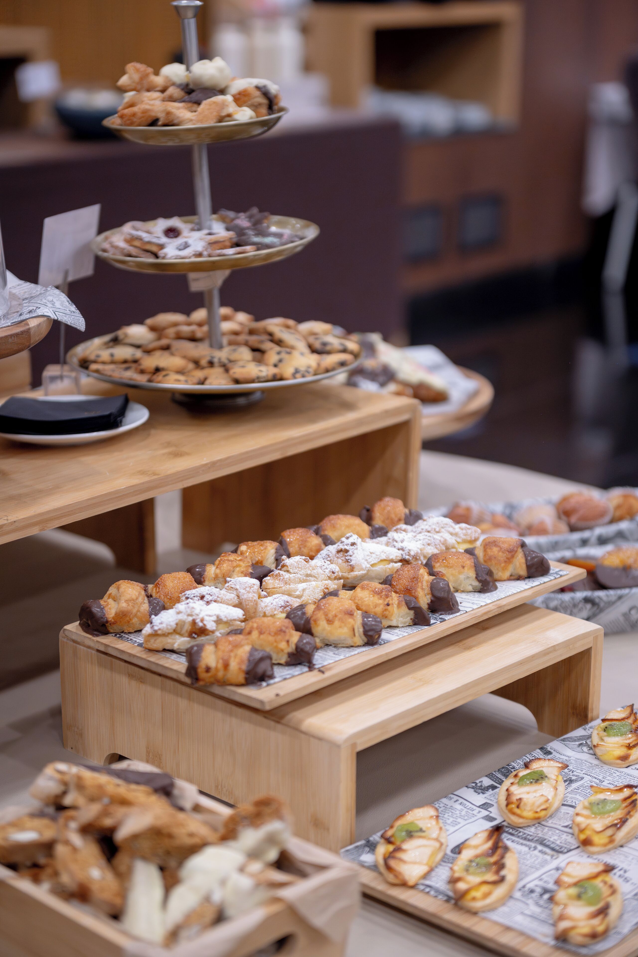 Een buffet met diverse gebakjes en desserts, gepresenteerd op houten presentatiestandaards.